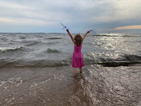 Katherine Hurd, five-years-old waves Marilyn Korzekwa into shore after swimming 16 hours across Lake Nipissing.