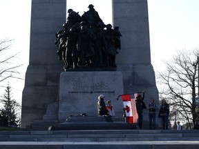 A person holds a combination American and Canadian flag at the Tomb of the Unknown Soldier at the National War Memorial before a march at a demonstration, part of a convoy-style protest participants are calling "Rolling Thunder”, in Ottawa, on Friday, April 29, 2022. THE CANADIAN PRESS/Justin Tang