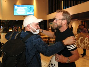 Artem Bandurko, left, hugs Fort City Church volunteer Jon Tupper after his family landed at Fort McMurray International Airport on July 11, 2022. Bandurko, his wife, infant son and mother-in-law are Ukrainian refugees settling in Fort McMurray. Vincent McDermott/Fort McMurray Today/Postmedia Network
