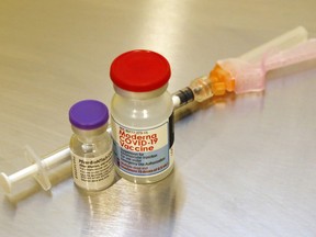 Vials of the Pfizer-BioNTech (left) and Moderna vaccines stand next to a syringe at Hastings Prince Edward Public Health in Belleville.