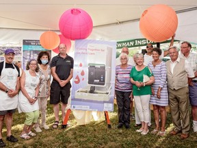 Attendees of the Incredible Doctors' Cook-off gather around a poster of a hematology analyzer. Funds raised during the July 8 event in Campbellford will help to buy the machine and a defibrillator for Campbellford Memorial Hospital.