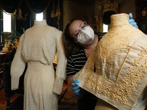 Glanmore National Historic Site's Danielle McMahon-Jones adjusts the collar of a semi-formal afternoon tea dress dating to around 1905 to 1910. At left is a seasonal white dress from between 1905 and 1915. They're among a dozen dresses, all from the Belleville area, on display this summer.