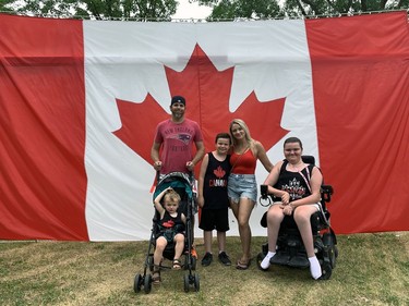 Matt and Mandy Rodrigues pose with their children, Clayton Rodrigues, 2, Zachary Duggan, 9, and Zoe Duggan, 12, in front of a giant Canadian flag set up for photos at Brantford's Canada Day celebrations. Susan Gamble