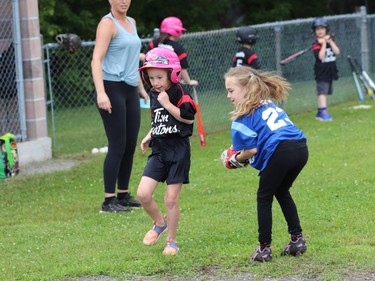 IT'S A HIT
Coach Stephanie DeJong looks on as Scarlett Walker runs past infielder Olivia Skinner after putting the ball in play during the final night of the Brockville Little League Baseball coach-pitch season on Wednesday. Just as the Brockville Fire Department was arriving to give the coach-pitch and Timbits t-ball players a fun shower, Mother Nature beat the firefighters to the punch and doused everybody at the Legion fields.
Tim Ruhnke/The Recorder and Times