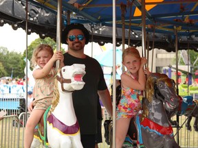 A family riding the carousel on the last day of Ribfest. From left Evley Wheeler,3, with father Nathan and niece Ava Ryan,7 on Sunday July 24, 2022 in Cornwall, Ont. Laura Dalton/Cornwall Standard-Freeholder/Postmedia Network