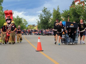 A team helmed by Brooks mayor Barry Morishita and pushed by his city's firefighters (left) faces off against a team featuring Cochrane's town council during the Cochrane Outhouse Races in 2019.