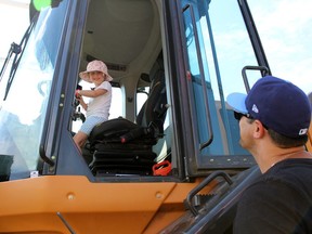 Matt Lavers and daughter Grace, 5, from Wyoming smile at each other while she checks out a piece of machinery during Plympton-Wyoming's Canada Day party on Saturday.  Terry Bridge/Sarnia Observer/Postmedia Network