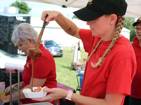 Jennifer Richard pours caramel sauce on apples during Plympton-Wyoming's Canada Day party on Saturday.  Terry Bridge/Sarnia Observer/Postmedia Network