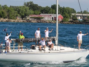 Crew members wave to spectators on shore as a sailboat on the St. Clair River heads for Lake Huron near Point Edward Saturday for the start of the annual Port Huron to Mackinac Island sailboat race.