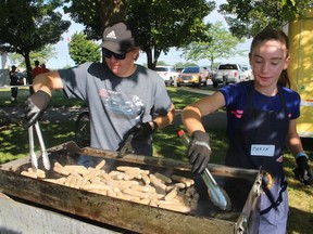 Robbie Gladwish, left, and Taryn Stoukas, grandchildren of the late Bob Gladwish, grill sausages during Saturday's Rotary Club of Sarnia Mackinac Breakfast in Point Edward's Waterfront Park.  Bob Gladwish, a Rotarian who died in December, was part of the breakfast's “sausage team” for many years.
