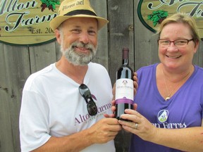 Marc Alton and Anne Kurtz Alton hold a bottle of their wine at Alton Farms Estate Winery in Plympton-Wyoming.