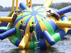 Kristin Ledoux, middle, her daughter, Hailey, 11, and Nolan Gagne, 12, and his brother, Dean, 16, hang on to one of the inflatables at the Splash N Go Adventure Parks Limited on Ramsey Lake in Sudbury, Ont. on Monday July 18, 2022. John Lappa/Sudbury Star/Postmedia Network