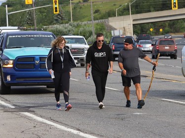 Chad Kennedy, right, president and founder of Sea to Sea for PTSD, is accompanied by James Jefferson and Rita Pede, of the Greater Sudbury Police, as he makes his way through Sudbury, Ont. on Wednesday July 27, 2022. Kennedy, who was with the Alberta Sheriff Highway Patrol, but is now off work indefinitely because of Post Traumatic Stress Disorder and anxiety, is walking across Canada to raise awareness Of PTSD while promoting the wellbeing of police, emergency services, including health-care workers, and military members. He began his journey in Cranbrook B.C. on April 4, 2022. "Funds raised during our walk across Canada will benefit mental health Initiatives revolving around our emergency service and military communities including our Northern Territories," said a statement on Kennedy's website. For more information, visit seatoseaforptsd.ca/home. John Lappa/Sudbury Star/Postmedia Network