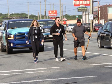 Chad Kennedy, right, president and founder of Sea to Sea for PTSD, is accompanied by James Jefferson and Rita Pede, of the Greater Sudbury Police, as he makes his way through Sudbury, Ont. on Wednesday July 27, 2022. Kennedy, who was with the Alberta Sheriff Highway Patrol, but is now off work indefinitely because of Post Traumatic Stress Disorder and anxiety, is walking across Canada to raise awareness Of PTSD while promoting the wellbeing of police, emergency services, including health-care workers, and military members. He began his journey in Cranbrook B.C. on April 4, 2022. "Funds raised during our walk across Canada will benefit mental health Initiatives revolving around our emergency service and military communities including our Northern Territories," said a statement on Kennedy's website. For more information, visit seatoseaforptsd.ca/home. John Lappa/Sudbury Star/Postmedia Network