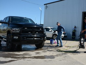 Family members of Pam Payne volunteering for Empire Details's fundraiser car wash pressure wash an attendee's truck on August 6. Empire Details offered car washes to raise funds for the Airdrie POWER women's shelter. Photo by Riley Cassidy/The Airdrie Echo/Postmedia Network