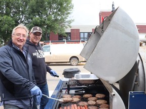Ron Kuehn and Dean McConnell flipped burgers at Royal LePage's grand opening.