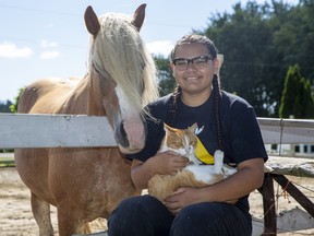 Sixteen-year-old Zhawanoogbiik Riley, shown here with her horse, Noodin, and her cat ,Gru, runs a pet food bank in Muncey. Derek Ruttan/Postmedia