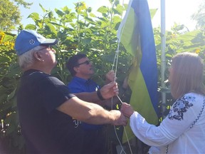 Orest Tiahur, left, Roger McRae, a Rotary Sunrise past-president, and Nina Zeleney, raise the Ukrainian flag during Saturday's grand opening of the 'Salute to Ukraine Rotary Park,' located at the corner of Grand Avenue East and Victoria Avenue in Chatham. (The Daily News)