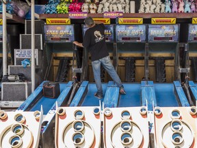 Michael De Grace cleans Skee Ball lanes on Wednesday as he works to set up midway games ahead of the 199th Quinte Exhibition in Belleville, Ontario. ALEX FILIPE