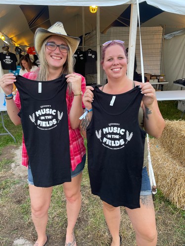 Jessica Simmons, left, and Caitlin Kennedy, both of Hanover, hold up souvenir t-shirts at Lucknow's Music in the Fields on Aug. 25. Photo by Kelly Kenny/Lucknow Sentinel.