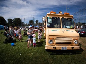 People purchase ice cream from one of Meedo Falou's Rainbow Ice Cream trucks, in Tsawwassen, B.C., on Monday, August 1, 2022. Much of Canada has been sweltering, but that’s cold comfort for ice cream truck vendors like Falou, who says inflation and high fuel costs are melting away his profits. THE CANADIAN PRESS/Darryl Dyck
