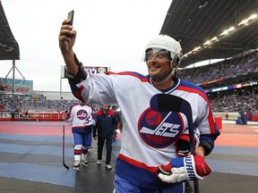Winnipeg Jets forward Teemu Selanne whips out his phone as he leaves the ice after the second period of the Heritage Classic alumni game against the Edmonton Oilers in Winnipeg on Sat., Oct. 22, 2016. Selanne is joining the Jets Hall of Fame. Kevin King/Winnipeg Sun/Postmedia Network