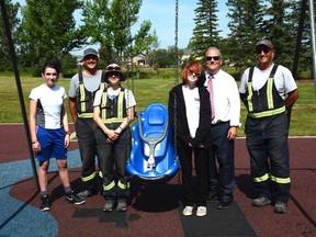 Mayor Peter Brown stands alongside Sayde P., a friend,and members of the City of Airdrie Parks team with Airdrie's latest swing, which is accessible for children with mobility hinderances. P. won the 2021 Mayor for a Day challenge with the idea for accessible playground equipment in the community. Photo by Riley Cassidy/The Airdrie Echo/Postmedia Network Inc.