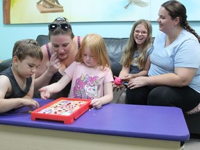 Parker's Project participant Kayla Cobbe (second from left) and her six-year-old daughter Brooklyn Fillion (center), play a game of Operation on Monday, Aug.  8 with Shayln Wilson (far right), another Parker's Project participant, and her children Blake Wilson, 5, and Harmony McGuin, 9, at the Park Road North office of Woodview Mental Health and Autism Services.  MICHAEL RUBY