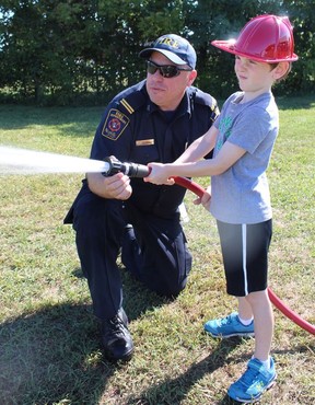 Six-year-old Rory Bain, whose dad Tyler Bain is a volunteer firefighter in Courtland, gets a lesson in firefighting on Saturday from fire prevention officer Cory Armstrong-Smith at the Norfolk County Annual Pump Competition, a fun contest involving local volunteer firefighters.  Michelle Ruby