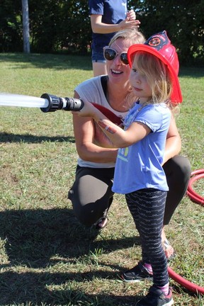 Jen Butindari helps her three-year-old daughter Paige keep a steady hand on Saturday in the kids' area at the Norfolk County Annual Pump Competition, a fun contest between local volunteer firefighters held in Courtland.  Michelle Ruby