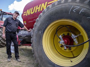 Jake Kraayenbrink, president of AgriBrink, shows a manure tanker outfitted with an air tank and lines to each tire, allowing the farmer to change tire inflation while operating the tractor during a soil compaction demonstration for farmers on Thursday.