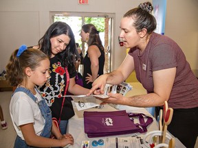 Zile Ozols (right) manager of programming and partnerships at the Brantford Public Library talks with Olga Anpilogova and her nine-year-old daughter Veronica on Wednesday at Newcomer Welcome Day at Mohawk Park.