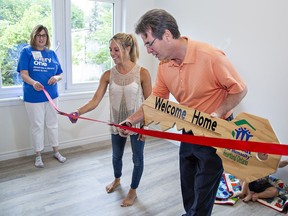 Kayla Ripley and Habitat for Humanity Heartland board chair Al MacKinnon cut the ribbon after she and her family were presented the keys to her new home on Willowdale Street in Brant County on Friday.