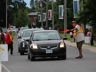 A traffic co-ordinator volunteer being kept busy as cars stream in. Photo on Saturday, July 30, 2022, in Maxville, Ont. Todd Hambleton/Cornwall Standard-Freeholder/Postmedia Network