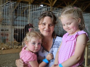 Grace (left) and Hope (right) Faith embrace their nana Jennefer Potts (centre) amidst the loud sounds of farm animals on Sunday August 28, 2022 in Chesterville, Ont. Shawna O'Neill/Cornwall Standard-Freeholder/Postmedia Network