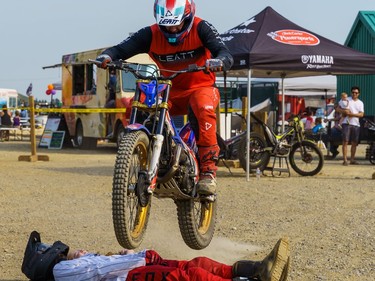 A motorcycle rider leaps over two people at the Cochrane fair on Friday, Aug. 19, 2022.