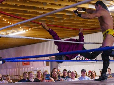 Fans watch as a wrestler is thrown out of the ring during CanAm Wrestling at the Cochrane fair on Friday, Aug. 19, 2022.