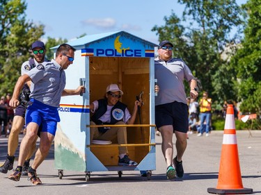 The RCMP team makes a turn during outhouse race action on 1st street in Cochrane on Sunday, Aug. 28, 2022.