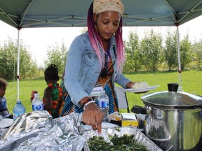 Rehoboth Alliance on Saturday, August 13, 2022 by J.J.  A woman serves food from Zambia at the Afro-Canadian Arts and Culture Festival held at Howard Pew Park.  Vincent McDermott/Fort McMurray Today/Postmedia Network