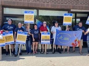 Striking safety inspectors and OPSEU members stand in front of Nipissing MPP Vic Fedeli's constituency office on Thursday.