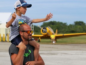 Ryan Carr, 7, waves at a pilot while sitting on dad John's shoulders during a fly-in event at the Sarnia Chris Hadfield Airport on Saturday.  Terry Bridge/Sarnia Observer/Postmedia Network