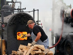 Mike Searson from Wyoming tosses wood into a boiler to power a steam engine donated by the former Belton Lumber company in Sarnia during the Western Ontario Steam Thresher's Association's event at the Forest Fairgrounds on Sunday.  Terry Bridge/Sarnia Observer/Postmedia Network