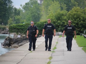 Sarnia police officers walk Sunday on the shore next to the Lambton Area Water Supply site in Sarnia while monitoring the start of the St. Clair River Float Down.