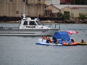 Participants in the St. Clair River Float Down Sunday wave to an OPP vessel as they head into the river at Sarnia.