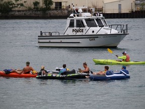 Participants in the St. Clair River Float Down pass an OPP marine unit Sunday afternoon after leaving from the shore in Sarnia at the start of this year's event.  An official said numbers appeared to be down this year.