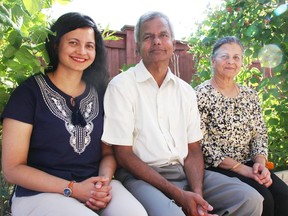 Compost helps grow various vegetables and fruits in the 24 raised garden beds in Indira, right, and Kumar, center, Radhakrishnan's backyard.  They're pictured with their daughter Gayathri, who helped them build the garden starting in 2015. (Tyler Kula/ The Observer)