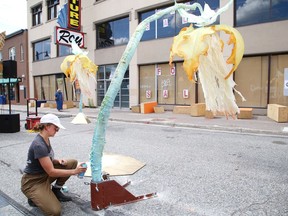 A woman works with an art installation on an urban downtown street