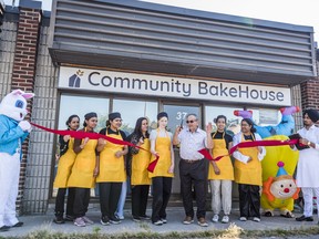 Councillor Garnet Thompson cuts the symbolic red ribbon in front of the Community Bakehouse Saturday morning in Belleville, Ontario. ALEX FILIPE