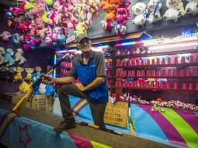 Carnival operator Randy Shea spins a cork-shooting gun as he looks to attract competitors to his shooting gallery at the Quinte Exhibition's midway on Saturday evening in Belleville, Ontario. ALEX FILIPE