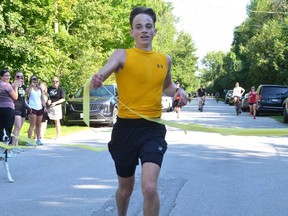 Jesse Walker of Balmy Beach breaks through the ribbon as he crosses the finish line after completing his third childhood cancer run on Saturday, September 3, 2022 in Georgian Bluffs. As of Saturday Walker had raised about $18,000 for cancer research and support services for paediatric cancer patients.